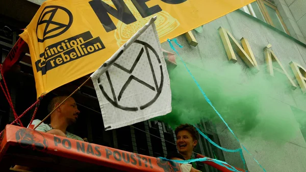 PRAAG, TSJECHIË, 28 juni 2021: Demonstratie Extinctie Opstand protestblokkade flara Bank, roken rookbom vrouw vastgebonden gebouw klimaatactivist oproerpolitie — Stockfoto