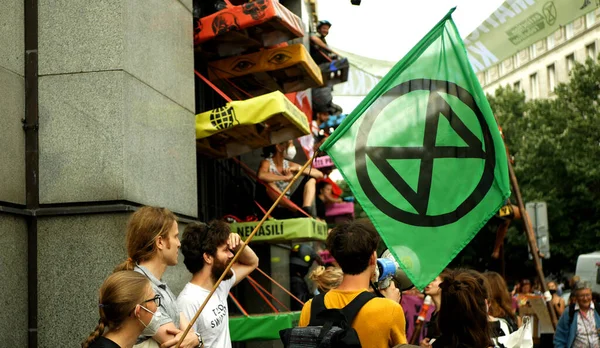 PRAAG, TSJECHIË, 28 juni 2021: Demonstratie Extinctie Opstand protestblokkade Bank, vlaggensymbool zandloper planeet waarschuwing vrouw vastgebonden gebouw klimaatactivist — Stockfoto