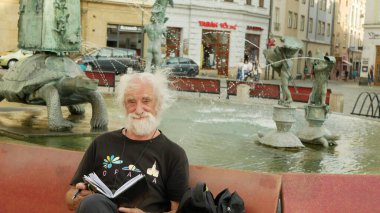 OLOMOUC, CZECH Cumhuriyet, 9 AĞUSTOS 2019: Dünyaca ünlü bir belgesel fotoğrafçısının Jindrich Streit portresi, Arion Fountain bir bankta oturuyor. Çek Üniversitesi öğretim üyesi, Avrupa