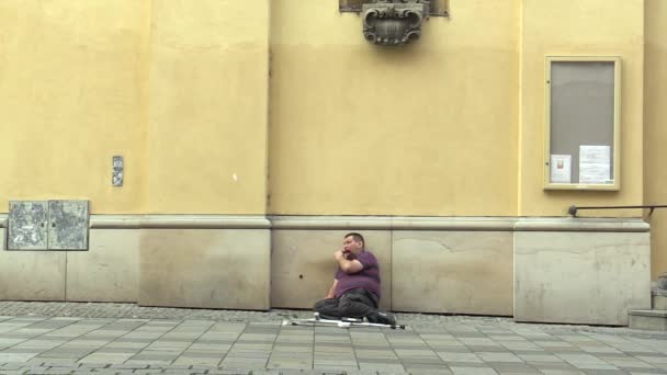 BRNO, CZECH REPUBLIC - AUGUST 27, 2015: Senior handicapped man homeless in city begging and plays the harmonica, South Moravia, Europe, EU — Stock Video