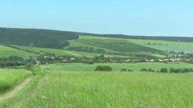 Yeşil dağlar (meadows), mavi gökyüzü ve Köyü