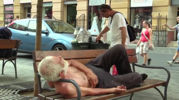 Brno, Tsjechië - 1 September 2015: Authentieke dakloze man ziet er uit de Prullenbak en dakloze man in slaap op een bank, Zuid-Moravië, Europa, Europese Unie — Stockvideo