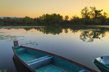     Güneşin doğuşunda bir gölde tekne 