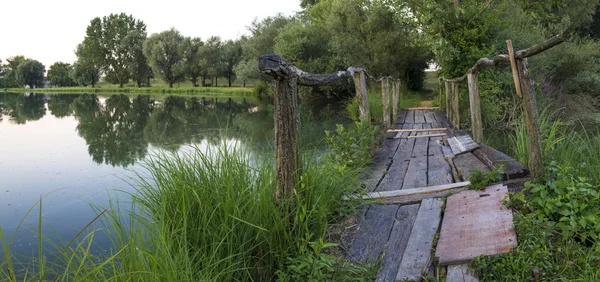 Puente de madera en un lago al amanecer — Foto de Stock