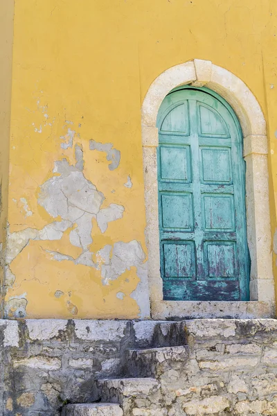 Antigua puerta verde rústica en una pared amarilla — Foto de Stock
