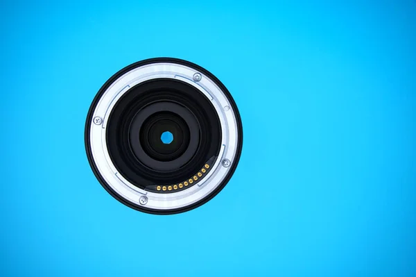 Lens of a full-frame mirrorless camera; mount with electrical contacts for lens data; blue background and copy space