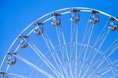 Bulutsuz mavi gökyüzüne karşı boş kamaraları olan beyaz dönme dolabın ayrıntıları