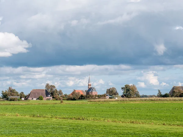 Polder füves területtel, parasztházzal és Cornjum templommal, Friesland, Hollandia — Stock Fotó