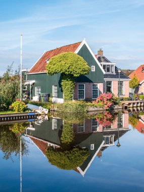 WARGA, NETHERLANDS - SEP 19, 2017: Wergea, Leeuwarden, Friesland köyündeki kanala yansıyan geleneksel ahşap ev