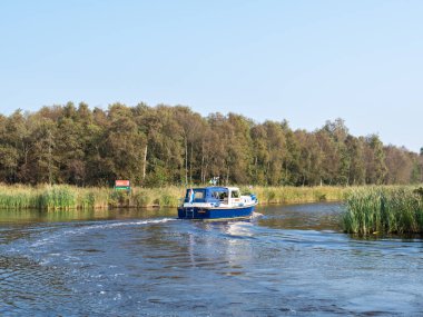 OUDE VENEN, NETHERLANDS - SEP 24, 2017: Motor yacht cruising on canal in national park Alde Feanen, Friesland