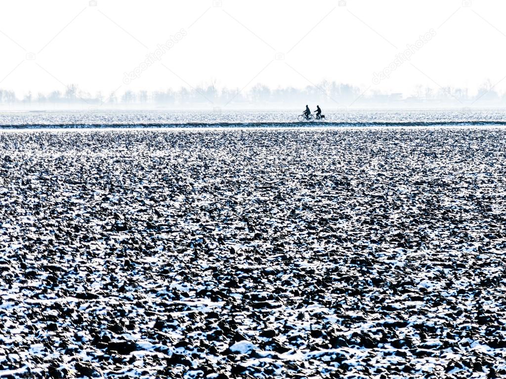 Two bicyclists in polder in winter, Holland