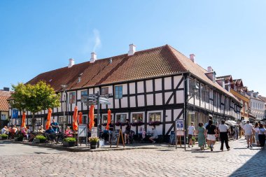 Ebeltoft, Danimarka - 9 Ağustos 2025: Eski Ebeltoft, Jutland 'da, Adelgade ve Jernbanegade' in köşesinde insanlarla ve yarı keresteli binalarla dolu bir kafeterya