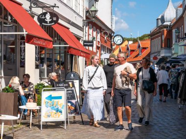 Ebeltoft, Danimarka - 9 Ağustos 2025: İnsanlar eski Ebeltoft, Jutland 'daki Adelgade kaldırım taşı alışveriş caddesinde geziniyorlar