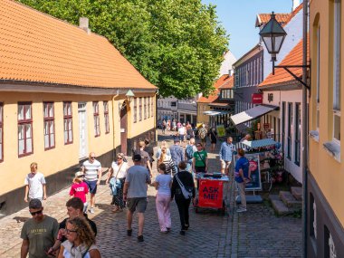 Ebeltoft, Danimarka - 9 Ağustos 2025: Eski Ebeltoft, Jutland, Danimarka 'da kaldırım taşları üzerinde yürüyen insanlarla Adelgade caddesi alışverişi
