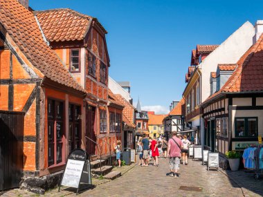 Ebeltoft, Danimarka - 9 Ağustos 2025: Eski Ebeltoft, Jutland, Danimarka 'daki Adelgade kaldırım taşı caddesinde gezinen insanlar