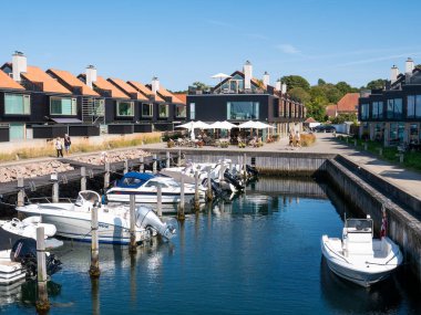 Ebeltoft, Danimarka - 9 Ağustos 2025: Sürat tekneleri, deniz kenarındaki daireleri ve Ebeltoft, Jutland, Danimarka 'daki liman boyunca yürüyen ve oturan insanlar olan küçük marina