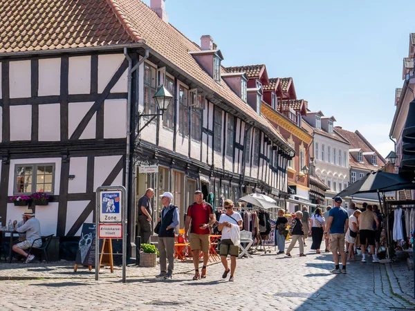 Ebeltoft, Danimarka - 9 Ağustos 2025: Danimarka 'nın eski kenti Ebeltoft, Jutland, Danimarka' da insanlar kaldırım taşı alışveriş caddesi Adelgade boyunca geziniyor