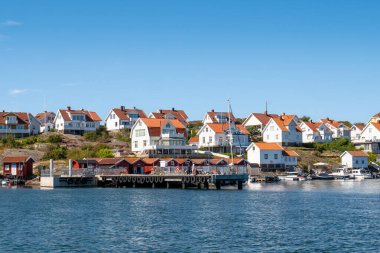 Gullholmen, İsveç - 16 Ağustos 2025: İskele ve Gullholmen kıyısı boyunca Bohuslan takımadasındaki Gullholmen adasındaki evler, batı kıyısı İsveç