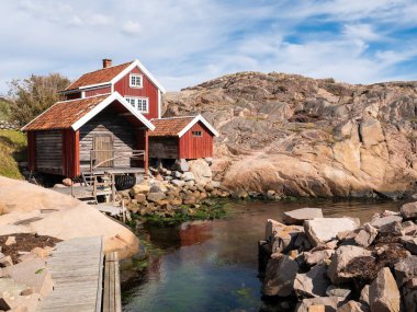 Lysekil, İsveç - 17 Ağustos 2025: İsveç 'in batı kıyısındaki Lysekil, Bohuslan' da granit kayalıkların yanındaki geleneksel ahşap kayıkhaneler