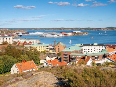 Lysekil, İsveç - 17 Ağustos 2025: İsveç batı kıyısındaki Bohuslan, Gullmarn fiord 'a doğru Rosviksberg tepesinden Lysekil limanı ve çatıları manzarası