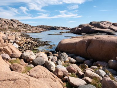 İsveç 'in batısındaki Lysekil, Bohuslan yakınlarındaki Staangehuvud doğa koruma alanında dağılmış kaya parçaları ve pürüzsüz kaya oluşumlarıyla Granit kayalık kıyı şeridi.