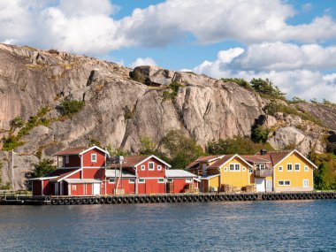 Grebbestad, İsveç - 22 Ağustos 2025: Grebbestad, Bohuslan, batı kıyısı İsveç 'te geleneksel ahşap balıkçılık binaları ve arka planda granit tepe Stoberget