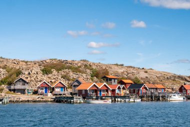 Heestrand, İsveç - 23 Ağustos 2025: Heestrand, Bohuslan, İsveç 'teki liman evleri, küçük marina ve ahşap binalı granit kıyı şeridi boyunca, batı kıyısındaki sessiz turistik olmayan kıyı köyü