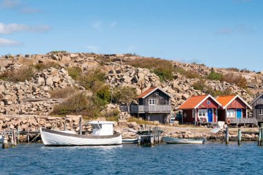 Heestrand, İsveç - 23 Ağustos 2025: Granit yamacın altındaki küçük ahşap evler Heestrand, Bohuslan, batı kıyısı İsveç 'teki taş ocakları.