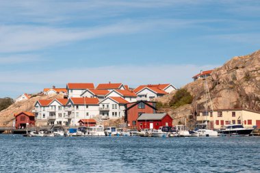 Kungshamn, İsveç - 24 Ağustos 2025: Hamnpromenaden, Kungshamn, Bohuslan, batı kıyısı İsveç 'te kayalık yamaçlarda tekneleri ve deniz kenarındaki daireleri olan liman