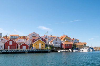 Grundsund, İsveç - 25 Ağustos 2025: Rıhtım evleri ve liman kanalı ile küçük tekneler Oso Adası, Bohuslan, batı kıyısı İsveç 'teki geleneksel balıkçı köyü Grundsund' da