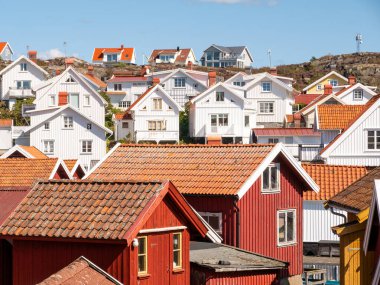 Grundsund, İsveç - 25 Ağustos 2025: Geleneksel beyaz ve kırmızı ahşap evler Skafto adasındaki Grundsund köyünde kırmızı kiremitli evler, Bohuslan takımadaları, batı kıyısı İsveç