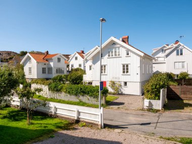 Grundsund, İsveç - 25 Ağustos 2025: Grundsund, Skafto Adası, Bohuslan Takımadası, İsveç 'in batı kıyısında Tunnan Caddesi boyunca bahçeli geleneksel beyaz ahşap evler