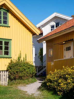 Gullholmen, İsveç - 26 Ağustos 2025 Bohuslan, batı kıyısındaki Gullholmen Adası 'nda sarı ahşap evler ve bahçe yolu
