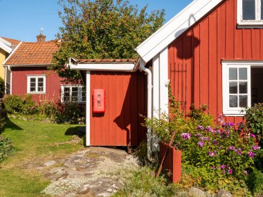 Gullholmen, İsveç - 26 Ağustos 2025 Bohuslan Takımadası 'ndaki Gullholmen Adası' nda kırmızı ahşap evler ve bahçe