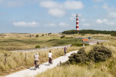 People cycling in dunes of Ameland, Netherlands clipart