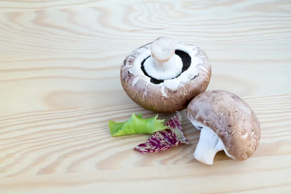 Chestnut mushrooms with lettuce leaf on wood — Stock Photo, Image