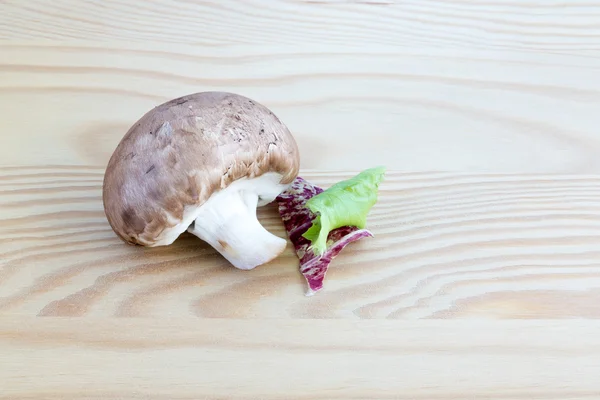 Chestnut mushroom with lettuce leaf on wood — Stock Photo, Image