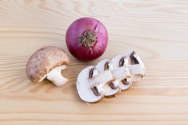 Chestnut mushrooms and red onion on wood clipart