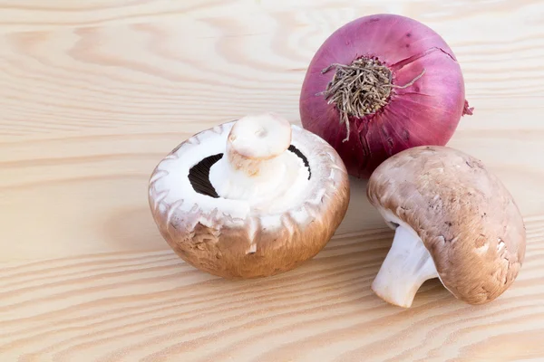 Chestnut mushroomsand red onion on wood — Stock Photo, Image