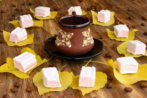 Cup of coffee in the center and yellow leaves with marshmallows — Stock Photo, Image