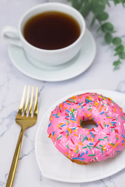 白い大理石の背景にピンクのドーナツと黒コーヒーのカップ — ストック写真