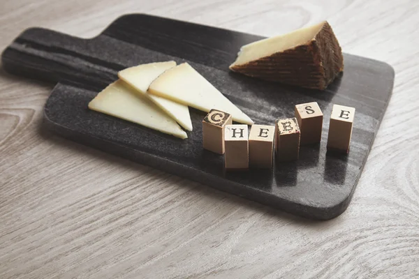 Letras de madeira lado a lado de queijo de cabra isolado — Fotografia de Stock