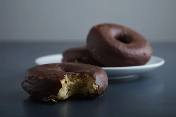 Unfocused choco donuts and focused bite — Stock Photo, Image