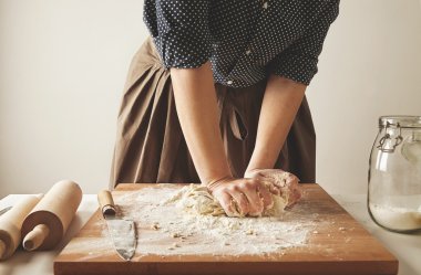 Woman kneads dough for pasta on wooden board clipart