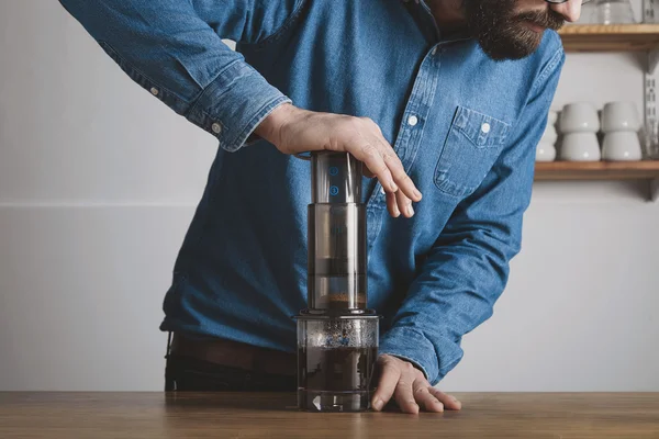 Bärtige Barista pressen Aeropress zum Füllen von Glas — Stockfoto