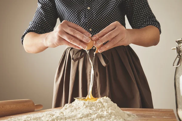 Mulher quebra ovo acima da farinha — Fotografia de Stock