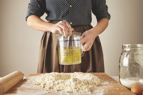 Donna mescolare l'acqua dell'olio d'oliva in tazza misura sopra la pasta — Foto Stock