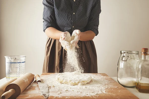 Frau gibt etwas Mehl zum Teig auf Holztisch — Stockfoto