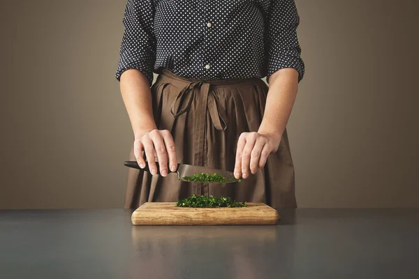 Woman holds knife above chopped green parsley — Stock Photo, Image