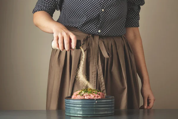 Focused housewife adds some garlic spices to unfocused minced me — Stock Photo, Image